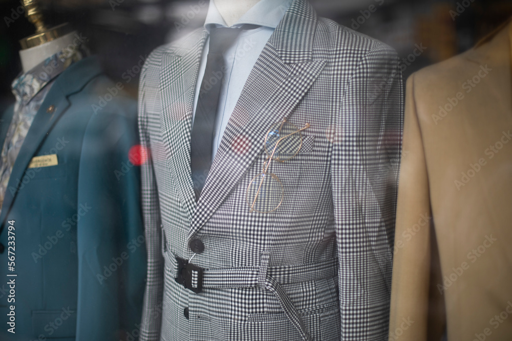 old fashioned men's suits through a shop window. Retro fashion with prince of wales check, creme colored jackets, shirts and ties. - obrazy, fototapety, plakaty 