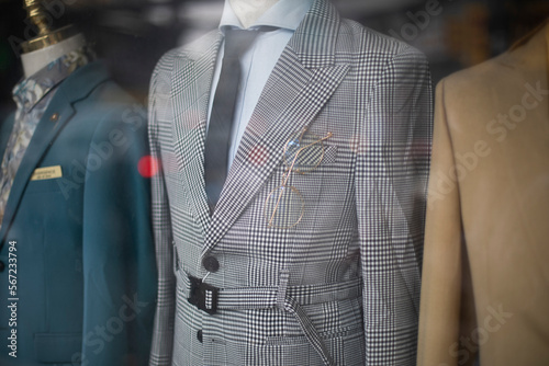 old fashioned men's suits through a shop window. Retro fashion with prince of wales check, creme colored jackets, shirts and ties. photo
