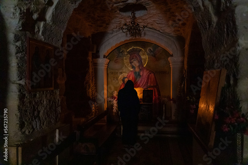 Believing woman stands and prays in front of the underground altar in the Monastery Deir Hijleh - Monastery of Gerasim of Jordan, in the Palestinian Authority, in Israel