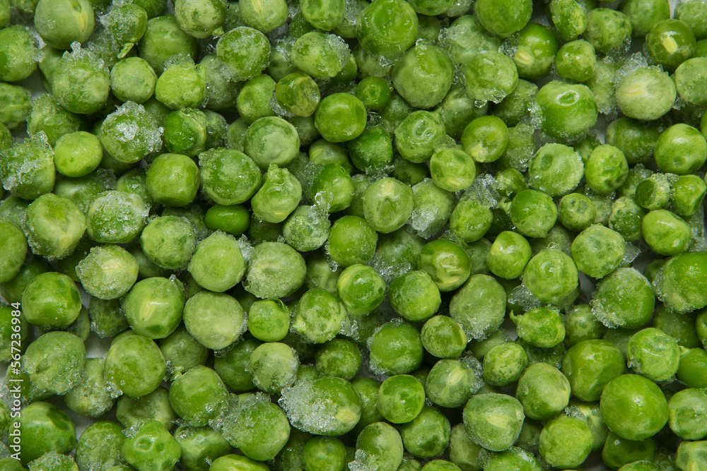 The texture formed by a scattering of green peas with pieces of ice, close-up The texture formed by a scattering of green peas with pieces of ice, close-up