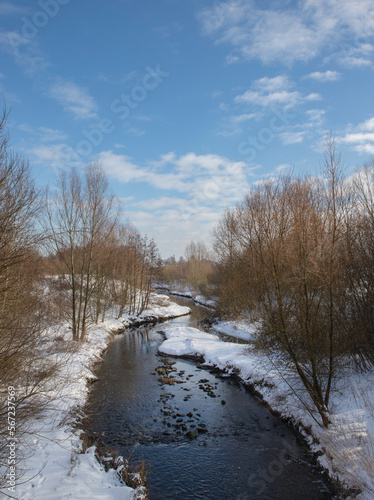 A river in a forest with frost in the background. a winter landscape with snow © Kateryna