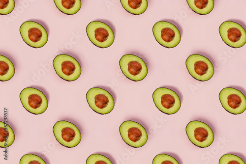 Pattern with halved avocados on pink background