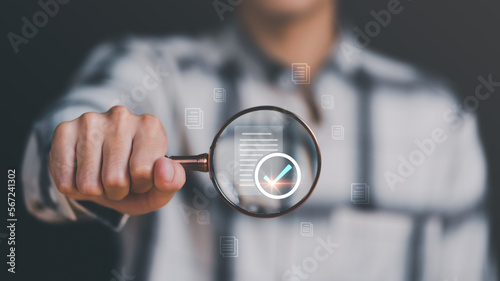 Businessman holding a magnifying glass, showing Audit Document concept,quality assessment management With a checklist, business document evaluation process, market data report analysis and consulting