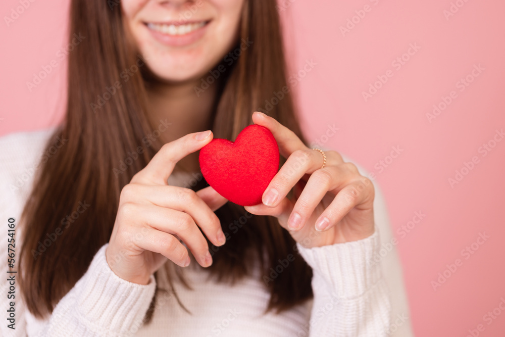 girl holding a heart in her hands close-up on a pink background, the concept of valentine's day girl holding a heart in her hands close-up on a pink background, the concept of valentine's day
