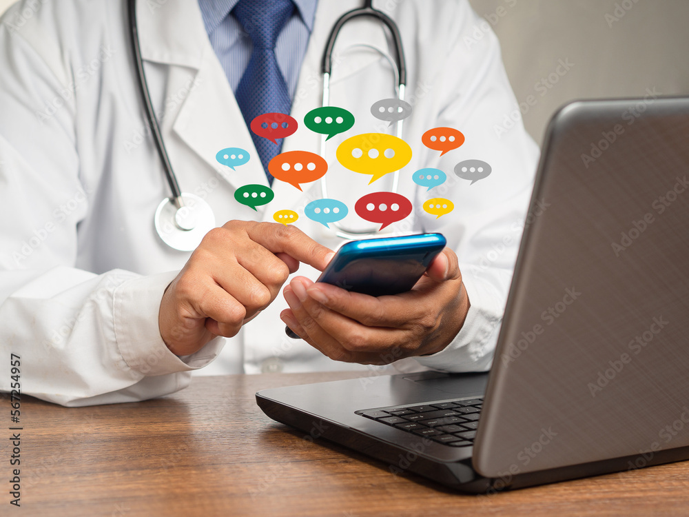 Doctor in a uniform using a smartphone with colorful chat icons on application digital web and social media while sitting at the table Doctor in a uniform using a smartphone with colorful chat icons on application digital web and social media while sitting at the table