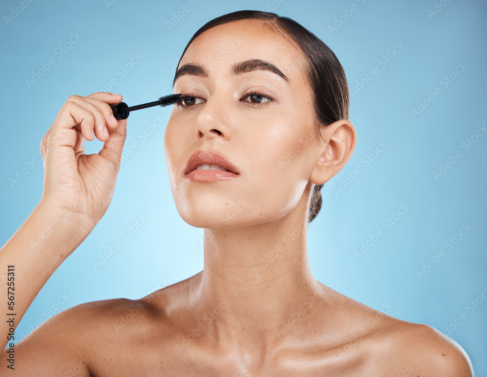 Mascara, application and woman with makeup on face isolated on a blue background in a studio. Beauty, glam and model with cosmetics from a brush on an eyelash for facial treatment on a backdrop