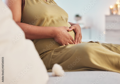 Pregnant stomach, couch and black woman hands with heart hand sign feeling mother love. Mom care, sofa and living room lounge with a person holding abdomen happy about pregnancy and baby in a house © T Mdlungu/peopleimages.com