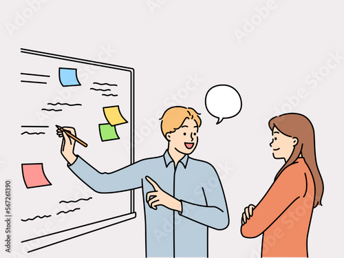 Man and woman employees of startup stand at whiteboard are brainstorming