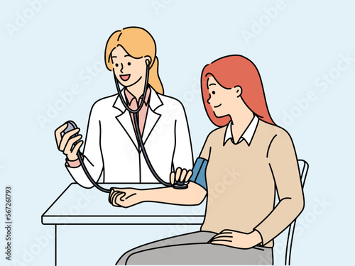 Woman undergoes medical examination at doctor using device for measuring pressure