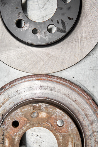 Old rusty brake disc and new disc. Change the old to new brake disc on car in a garage. Auto repair concept.