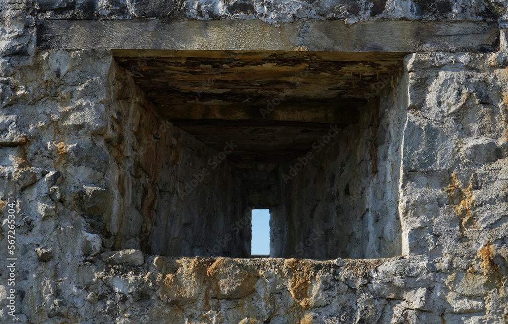 Stone wall with a square opening. Sky  view. Old fortress. Historical Petra Fortress  between Batumi  and Kobuleti towns. loophole in a fortress with a narrow window. grey stone wall. inside view.