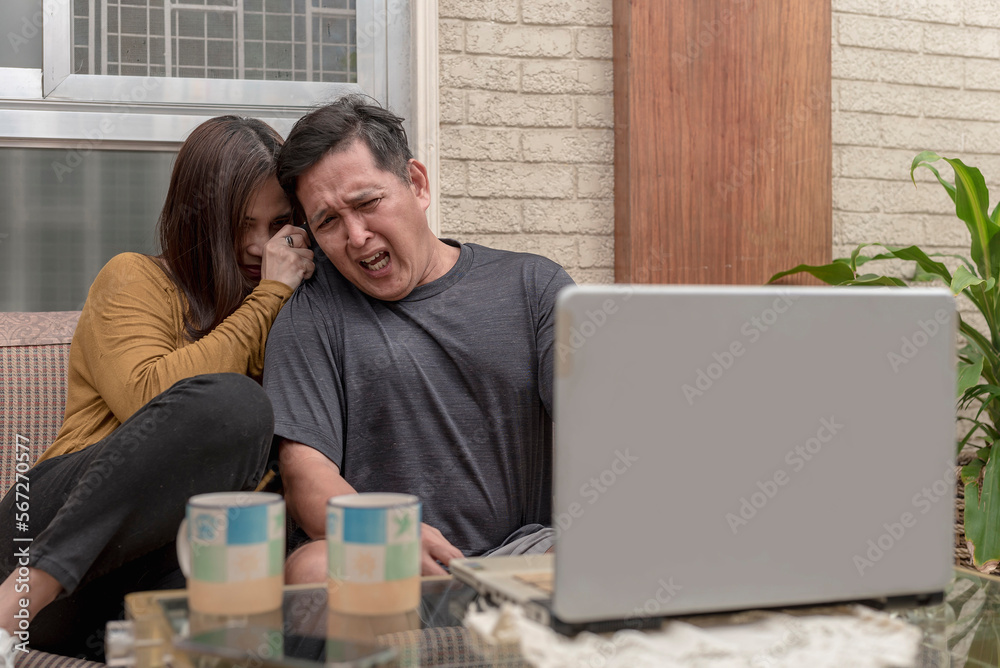Φωτογραφία An asian couple squeals and cringes in disgust while watching a gory horror movie on their laptop at the living room