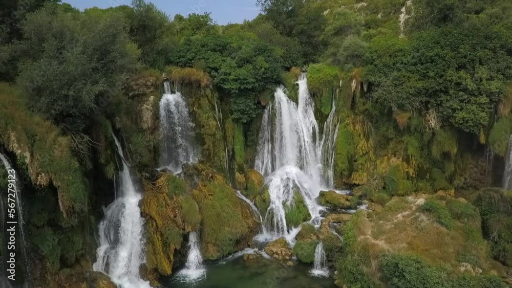 Aerial pulls back from Kravice waterfall in dense green Bosnian forest Aerial pulls back from Kravice waterfall in dense green Bosnian forest