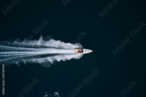 Big white high performance motorboat with orange seats move faster on dark water top view © Berg
