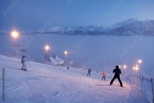 Fotografia, Obraz Ski slope with silhouettes of skiers descending on Gubałowka hill, Tatras Mountains, Zakopane, Poland