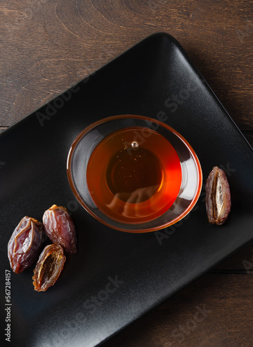 Natural organic healthy date syrup in a glass bowl with whole dates on the background. Top view