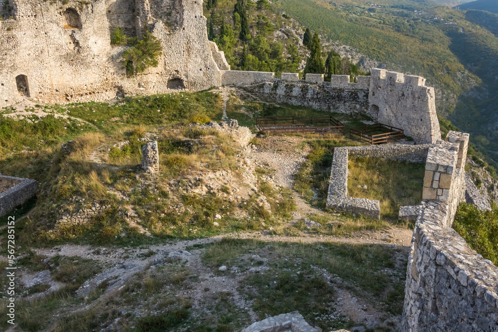 Ruins of a medieval castle with vegetation coming back and a panoramic view of the valley bellow