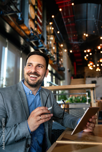 Young smiling successful business man, entrepreneur in formal business suite working on tablet