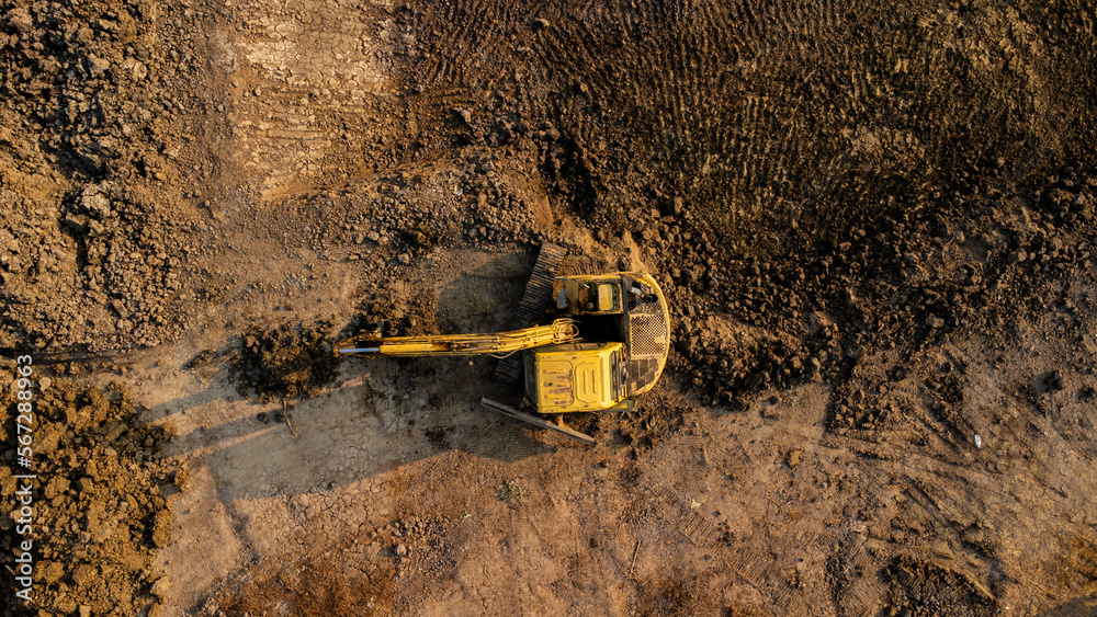Excavator dig ground at construction site. Aerial view of a wheel loader excavator with a backhoe loading sand into a heavy earthmover. Excavator digging soil pits for the agricultural industry.