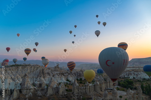 Many beautiful colorful balloons in the sky at a fabulous sunrise over the rocks, mountains in Goreme
