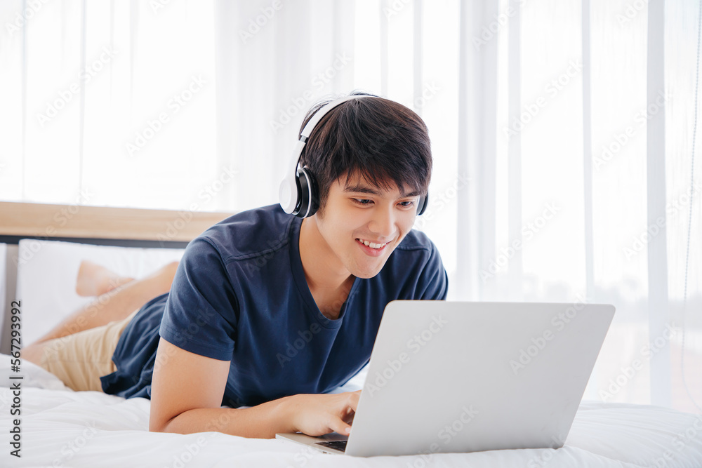 Happy man using Laptop computer and checking good News in the Bedroom. COPY SPACE. Trading. Watching Movie. WORK FROM HOME WFH Concept. Happy man using Laptop computer and checking good News in the Bedroom. COPY SPACE. Trading. Watching Movie. WORK FROM HOME WFH Concept.