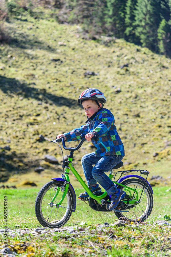 Kleiner Junge befährt mit seinem Rad einen Feldweg im Frühling Kleiner Junge befährt mit seinem Rad einen Feldweg im Frühling