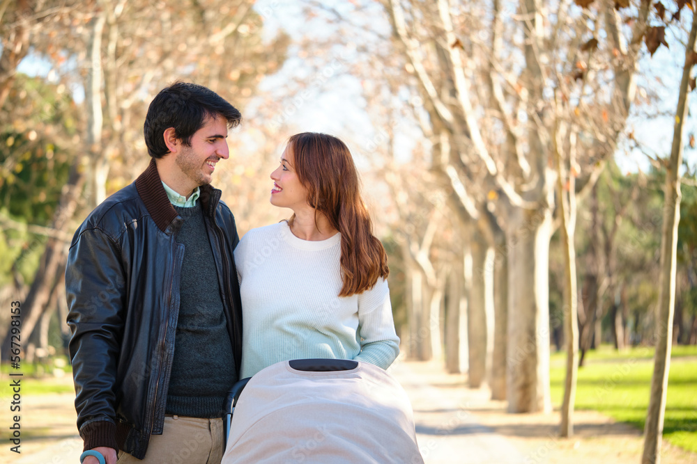 Couple looking at each other with a baby stroller in a park. Couple looking at each other with a baby stroller in a park.