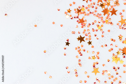 Glittering gold colored stars and crystals confetti on a blue background. Festive concept with copy space. Selective focus.
