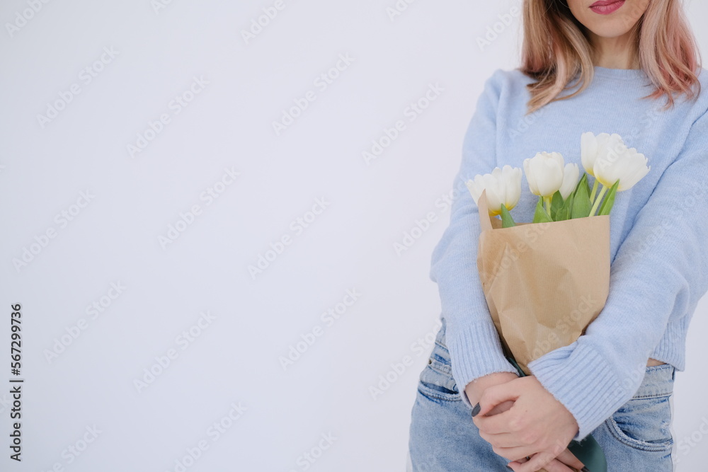 Young beautiful woman holding and hugging a bouquet of white tulips. Love celebration concept. Self love concept. Woman's day. Woman day. Gift concept for woman celebration. Feminine. Delicate Young beautiful woman holding and hugging a bouquet of white tulips. Love celebration concept. Self love concept. Woman's day. Woman day. Gift concept for woman celebration. Feminine. Delicate