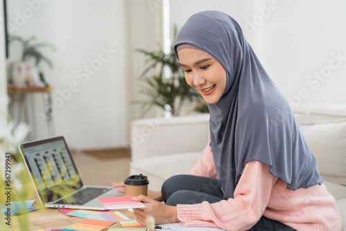 Asian young Muslim woman graphic designer wear hijab headscarf working and design color swatches samples with laptop computer in the workshop. Interior design and renovation concept