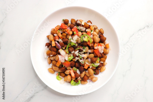 High in protine boiled black chana or chickpea salad. Chopped tomatoes, onion, chilies, and coriander mixed with boiled peanuts or bengal gram. Weight loss meal. Served with Lemon. Copy space.