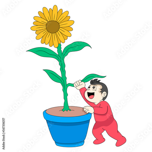 baby boy is having fun reaching for the sunflower in the pot