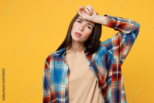 Young sad sick ill caucasian woman wear blue shirt beige t-shirt look camera put hand forehead head suffer from headache isolated on plain yellow background studio portrait People lifestyle concept