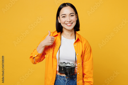 Traveler satisfied fun woman wear summer casual clothes camera show thumb up isolated on plain yellow background. Tourist travel abroad in free spare time rest getaway Air flight trip journey concept #567308309