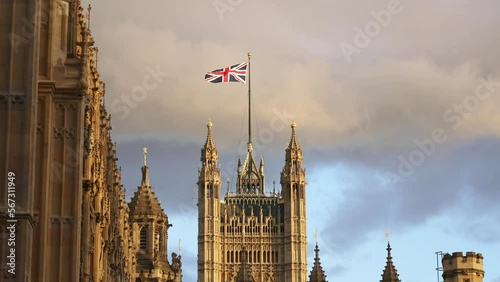 Flag of Great Britain, Palace of Westminster, Houses of Parliament in London. English tourism destination, iconic landmark, travel in England. 4k slow motion. Union Jack flag. 
