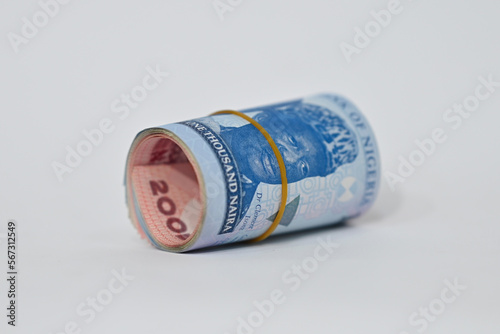 roll of new Naira tied with rubber band laying on white tabletop