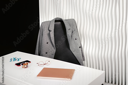 Head office. Armchair and stylish jacket, modern workplace with laptop on the table.