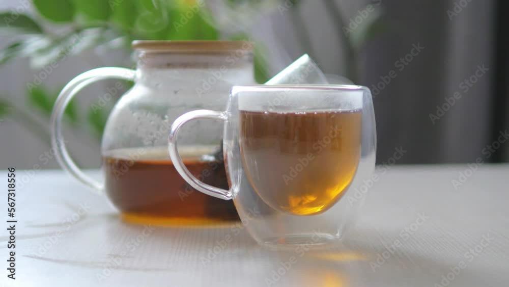 Composition with teapot and cup of flower drop tea on white table against backgroundv