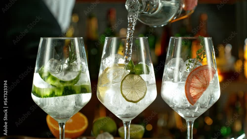Super slow motion of preparing gin and tonic drinks with speed motion. Filmed on high speed cinema camera, 1000 fps, placed on high speed cine bot. Bar with bottles on background. Speed ramp effect.
