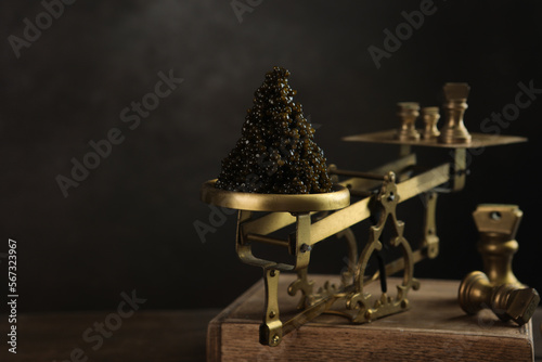 Black caviar. Black caviar is on the scales. Delicacy of sturgeon fish. Brass antique scales. A symbol of wealth and luxurious life. A useful omega.Photo with space copy.