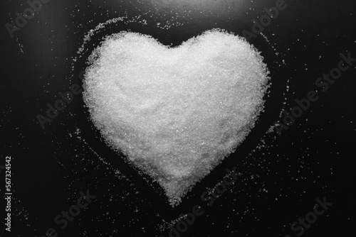 Abstract black and white photo in retro style with image of sweet heart made of white sugar on black background