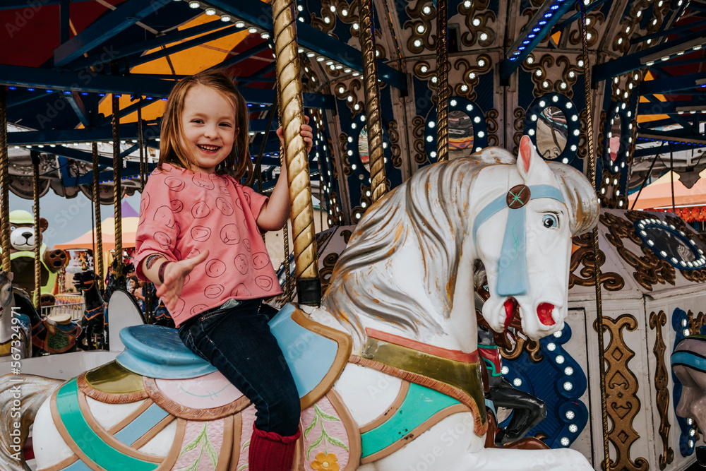 Portrait of happy cute girl riding on carousel at amusement park Portrait of happy cute girl riding on carousel at amusement park