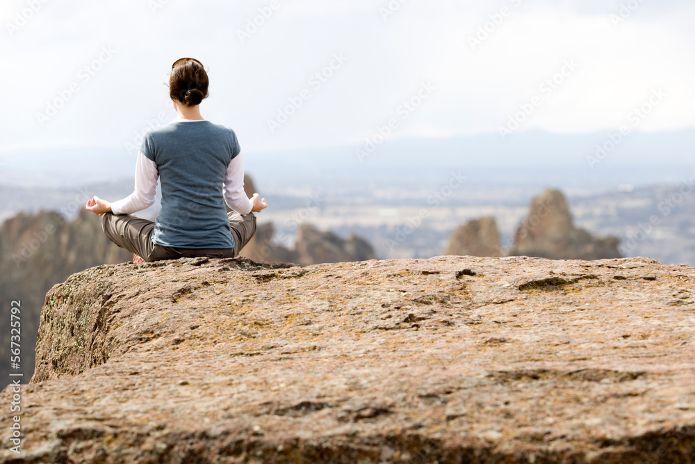 A woman meditating on the edge of a cliff. A woman meditating on the edge of a cliff.