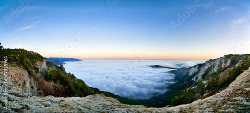 Cloudy mountain valley sunrise summer landscape panorama. Rocky Carpathian meadow panoramic view. Bright landscape in the morning light with beautiful green grass and clear blue sky. Panoramic view.