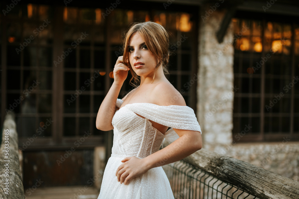 Beautiful bride portrait standing on wooden bridge in front of stone building Beautiful bride portrait standing on wooden bridge in front of stone building