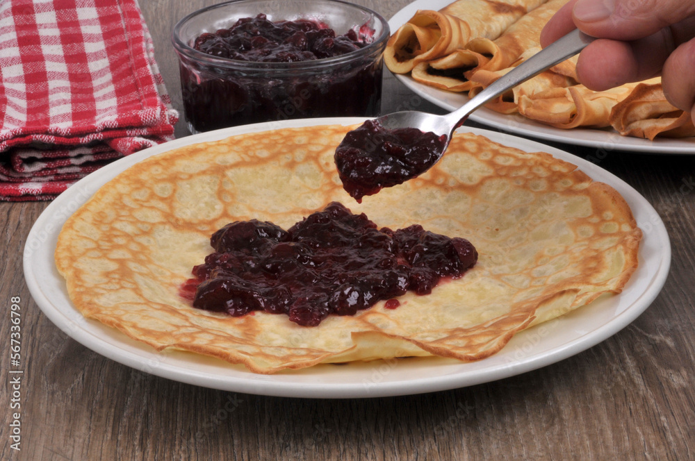 Mettre de la confiture sur une crêpe avec une cuillère Mettre de la confiture sur une crêpe avec une cuillère
