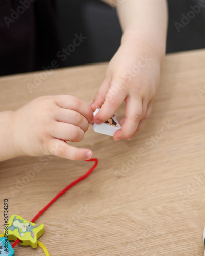 Child plays with beads and string. Fine motor skills development. Early education, Montessori Method