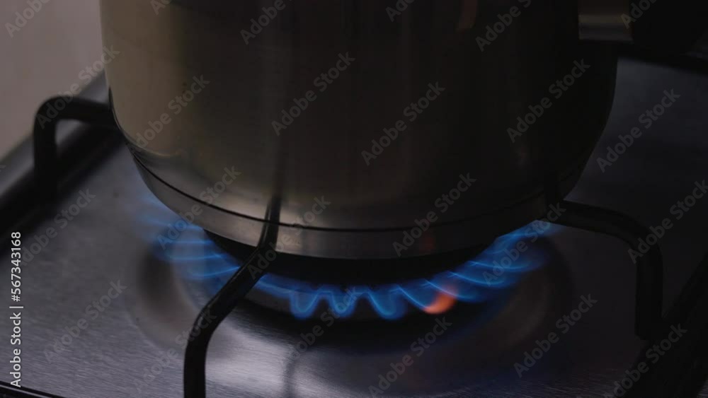On the gas stove with pot on it gas burns with a large blue flame. The