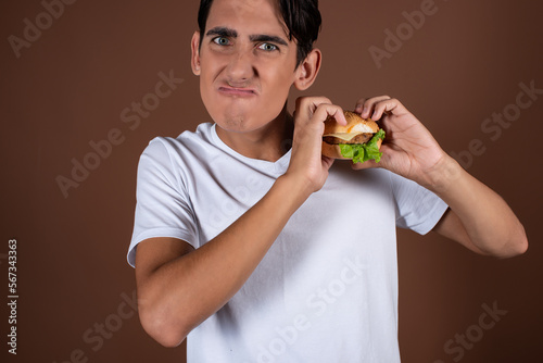 Portrait of a thin man. The guy chooses between fast food and a healthy lifestyle. Diet. Brown background. © Denis