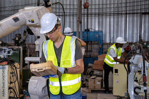 In robotic maintenance shop engineer busy commissioning and operate robot arm after programming